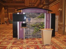 RENTAL Exhibit -- Pavilion with multiple 10&acirc;�� exhibits, arch-shape canopies with black covers, Sintra accent wings, tapered counter workstations, 16&acirc;�� high exhibits, kiosks -- Image 1