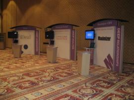 RENTAL Exhibit -- Pavilion with multiple 10&acirc;�� exhibits, arch-shape canopies with black covers, Sintra accent wings, tapered counter workstations, 16&acirc;�� high exhibits, kiosks -- Image 2