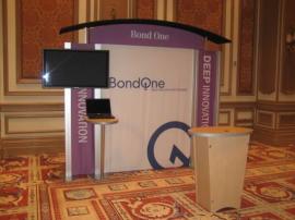 RENTAL Exhibit -- Pavilion with multiple 10&acirc;�� exhibits, arch-shape canopies with black covers, Sintra accent wings, tapered counter workstations, 16&acirc;�� high exhibits, kiosks -- Image 3