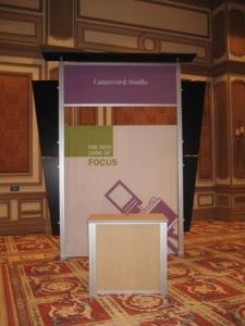RENTAL Exhibit -- Pavilion with multiple 10&acirc;�� exhibits, arch-shape canopies with black covers, Sintra accent wings, tapered counter workstations, 16&acirc;�� high exhibits, kiosks -- Image 5